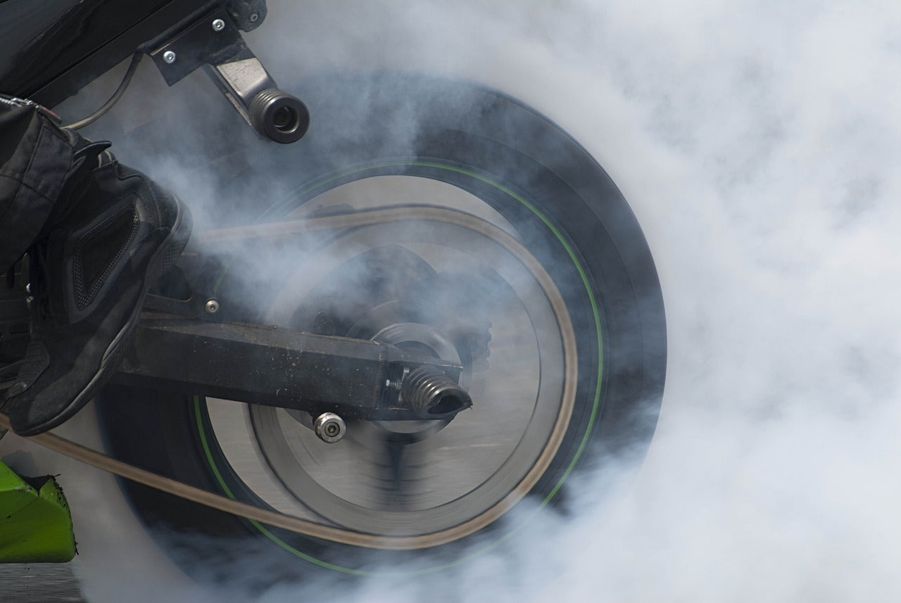 Behold the thrilling sight of a motorcyclist, her bike's rear wheel ablaze with power, as she accelerates while keeping the brakes engaged, creating a mesmerizing display of controlled  burning rubber